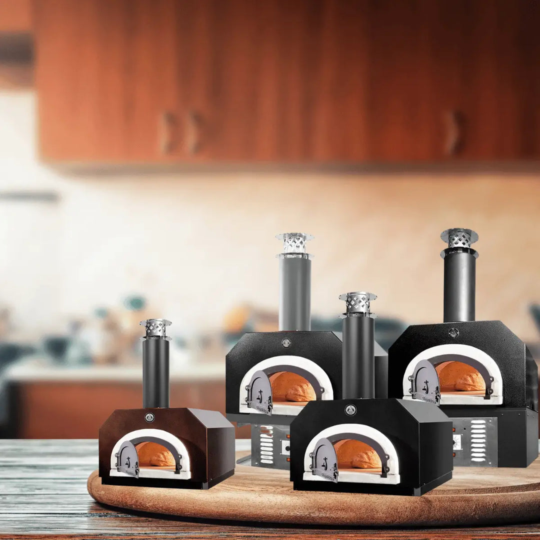 Chicago Brick Oven countertop pizza ovens in black, stainless steel, and wood finishes, displayed in a modern kitchen with wood-fired bread inside.