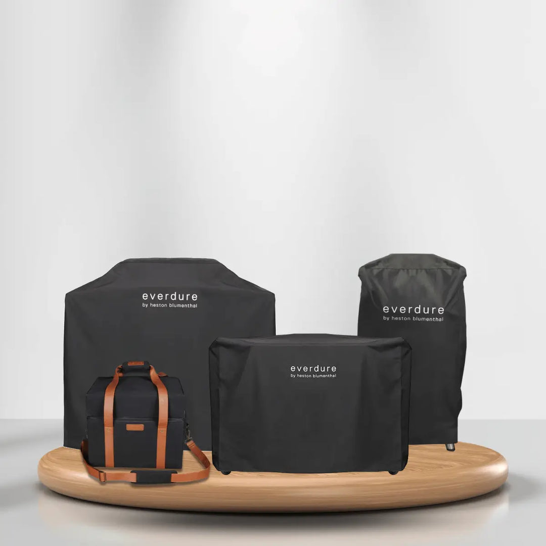 Everdure grill covers collection with weatherproof covers and carrying bag on wooden platform for outdoor grill protection and storage.