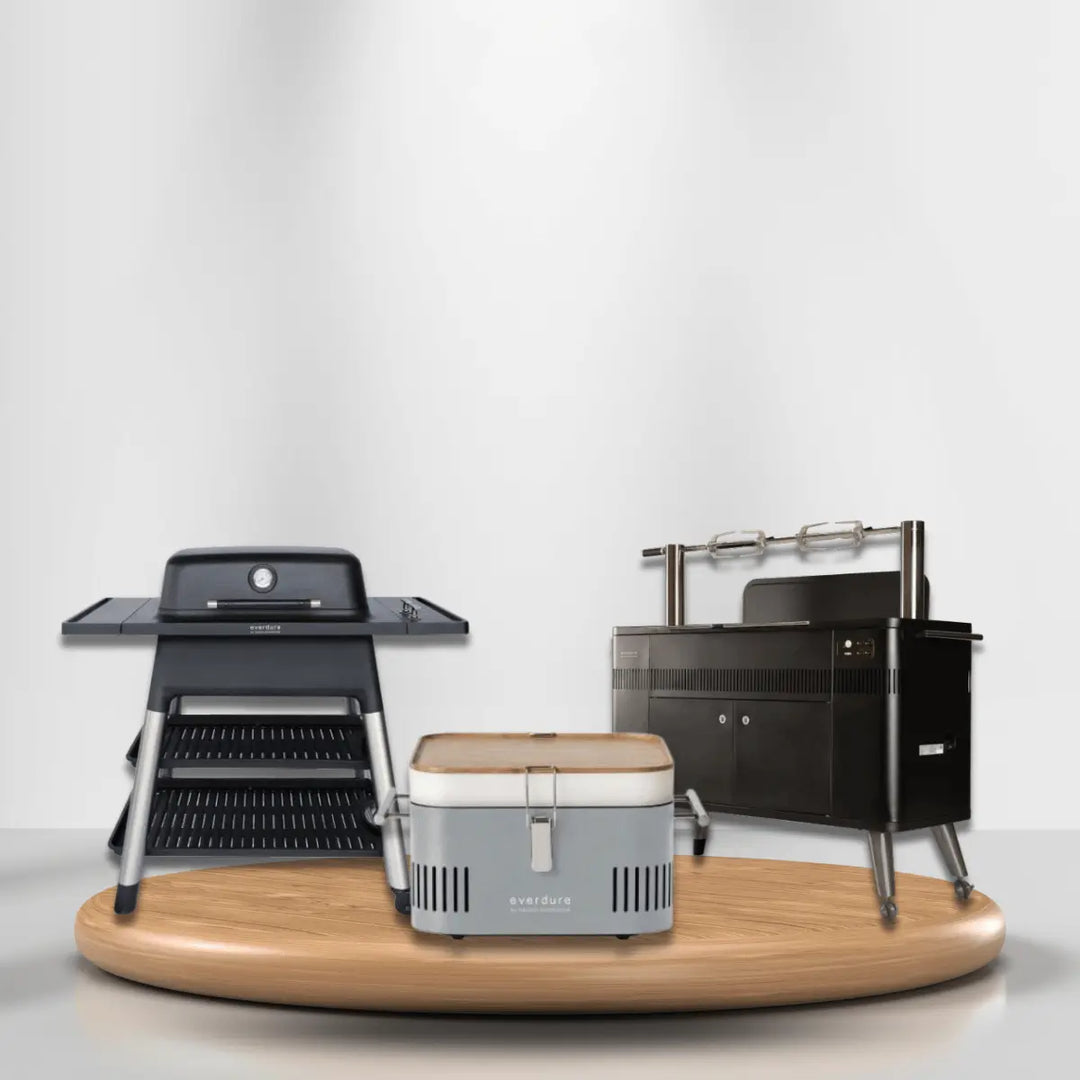 Everdure grills collection featuring charcoal grill, portable cooler grill, and premium rotisserie grill on modern display platform.
